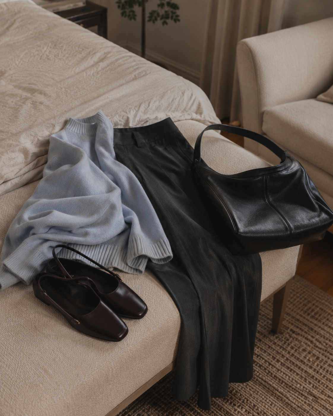 A fine knit, straight trousers, leather flats, and a soft work bag arranged for an ordinary workday.